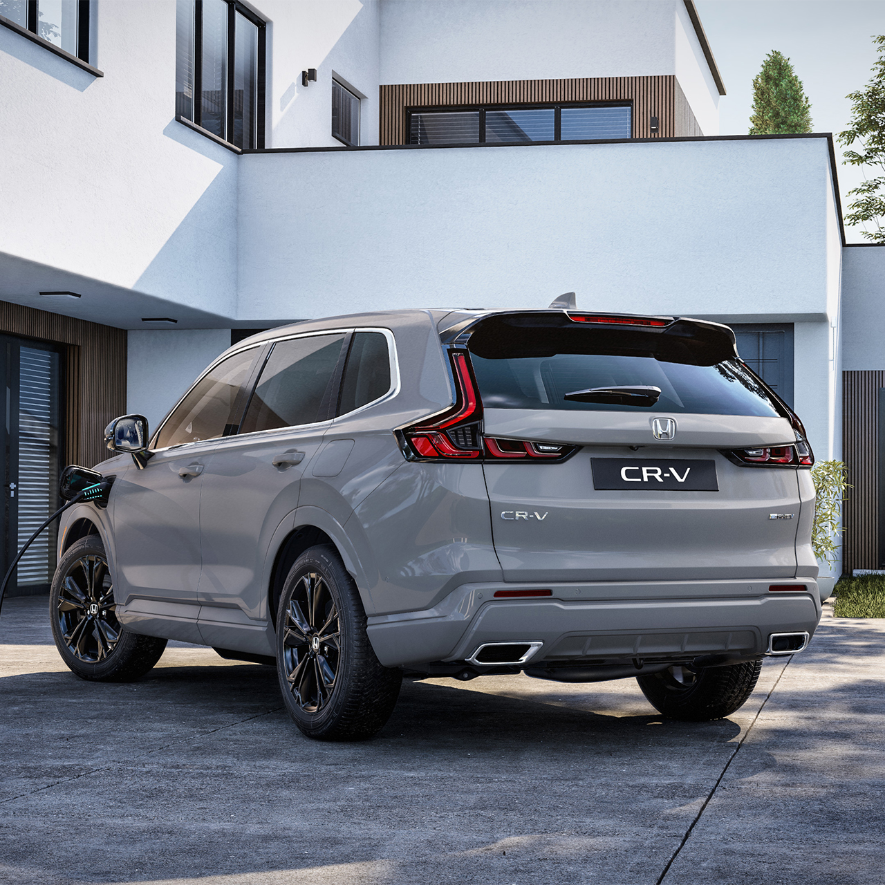 Vista trasera de tres cuartos del Honda CR-V Plug-in Hybrid enchufado para cargar.
